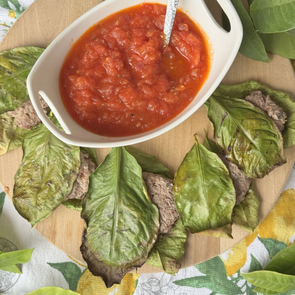 Lemon leaf wrapped meatballs on a wooden board.