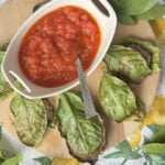 Lemon leaf wrapped meatballs on a wooden board.