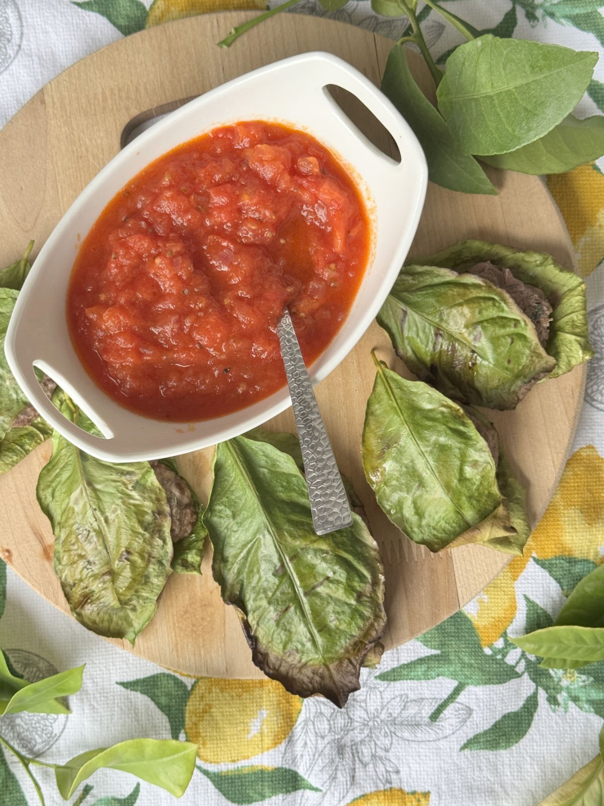 Lemon leaf wrapped meatballs on a wooden board.
