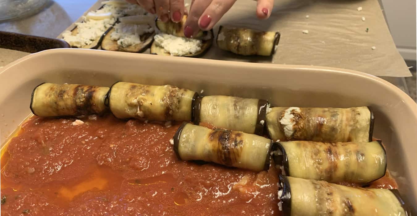 Rolling the eggplant slices and placing them into the baking sheet.