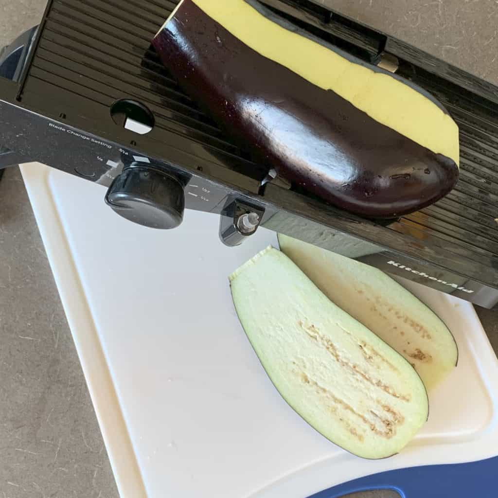 Slicing the eggplants on a mandoline slicer.
