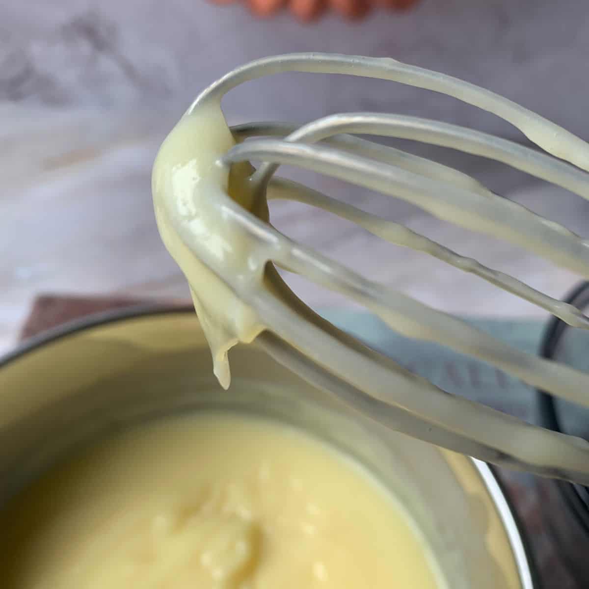 Cooked custard in a pan and whisk.