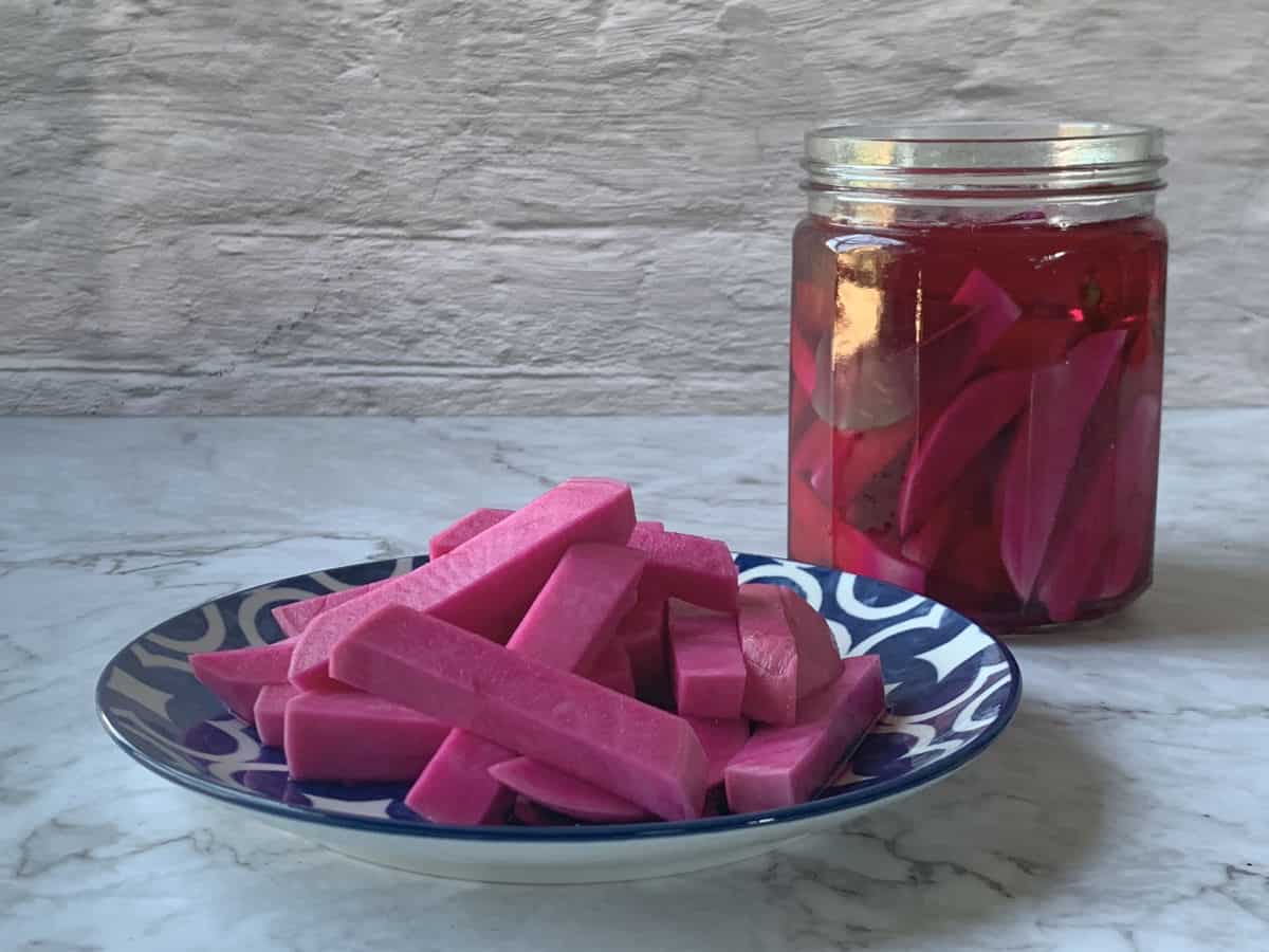 Jar of pickled turnip on a counter with a pink baton on the plate.