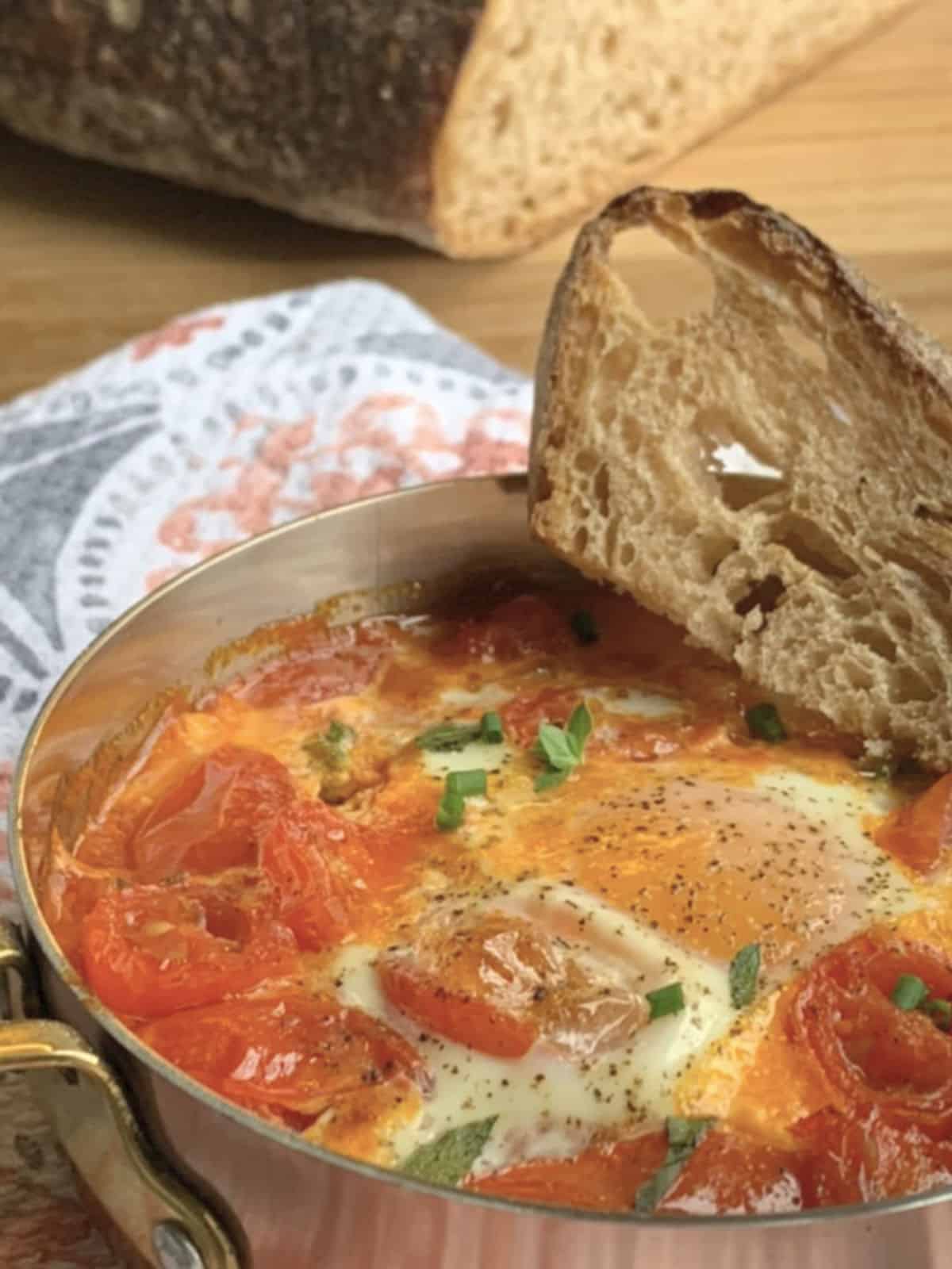 The shirred eggs  and tomato confit in a small copper pan with a crusty bread. 