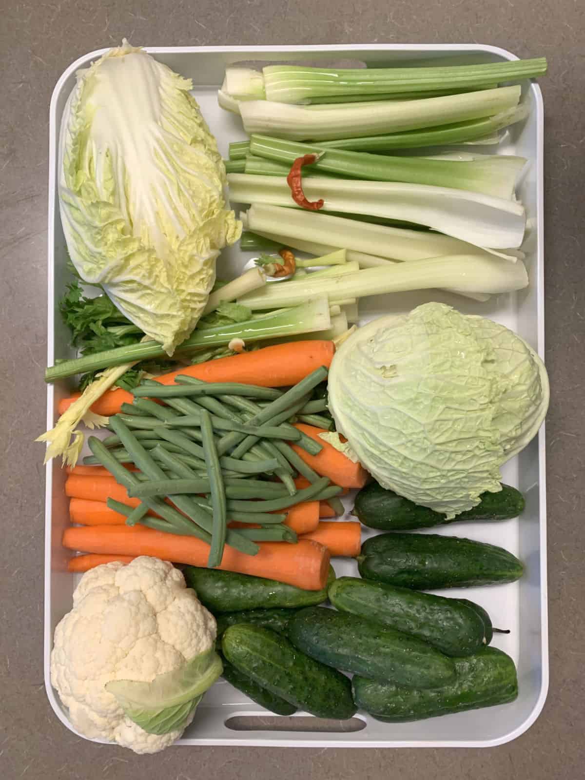 Cabbage, cucumber, beans, carrots, celery, cauliflower on a sheet pan.