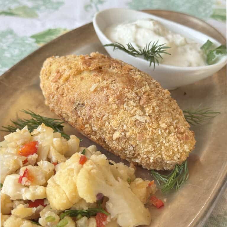 A close-up of a potato kofta with cauliflower rice and yogurt dip, showcasing its rich layers and textures.