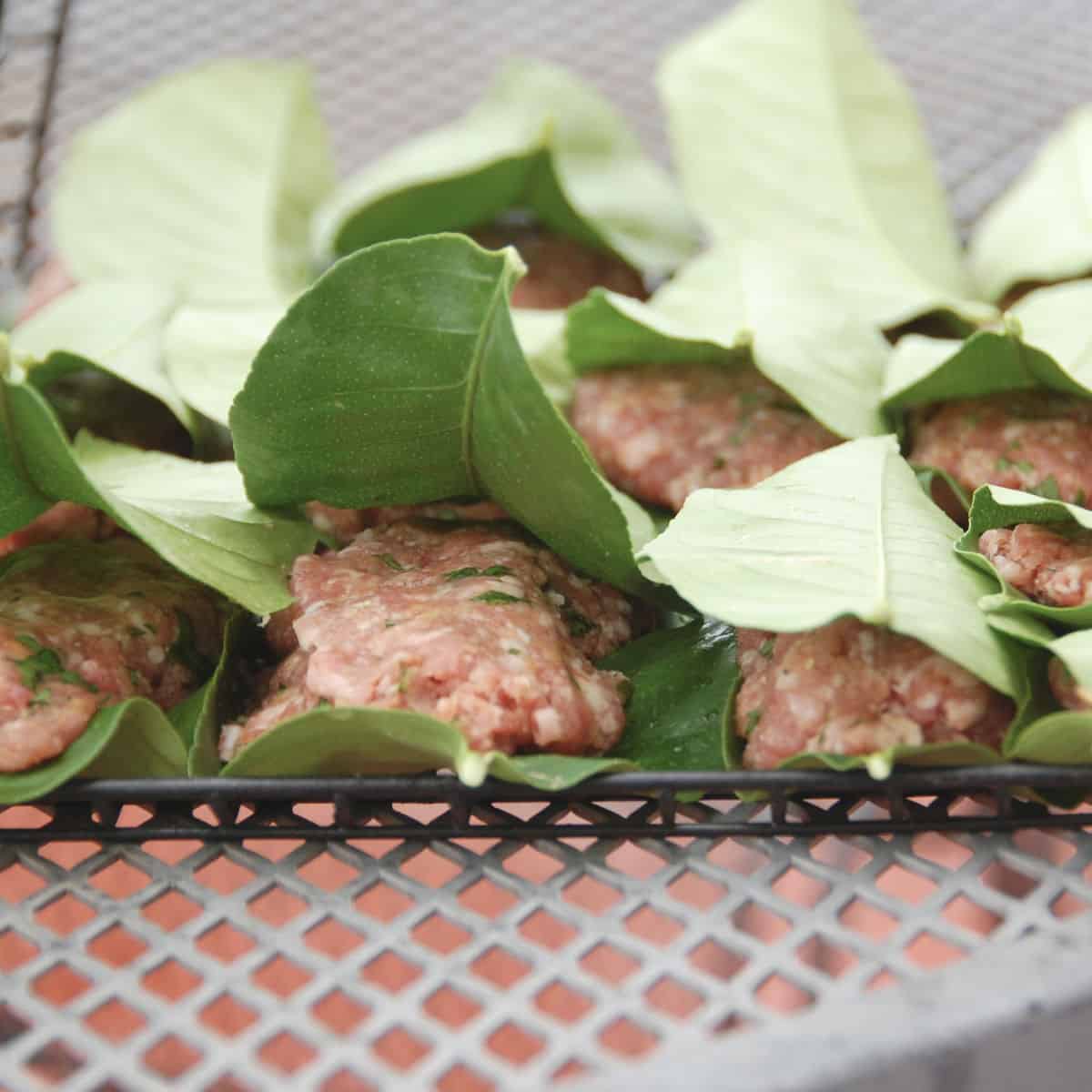Meatballs are arranged in a grilling basket.