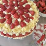 Strawberry cake with red plates and bowl of strawberries.