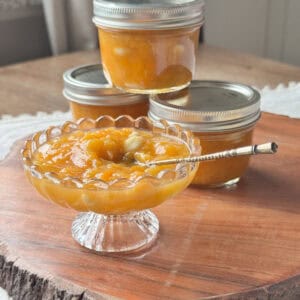 Apricot jam in a vase and a coupe of jars in the background.