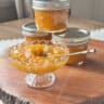 Apricot jam in a vase and a coupe of jars in the background.
