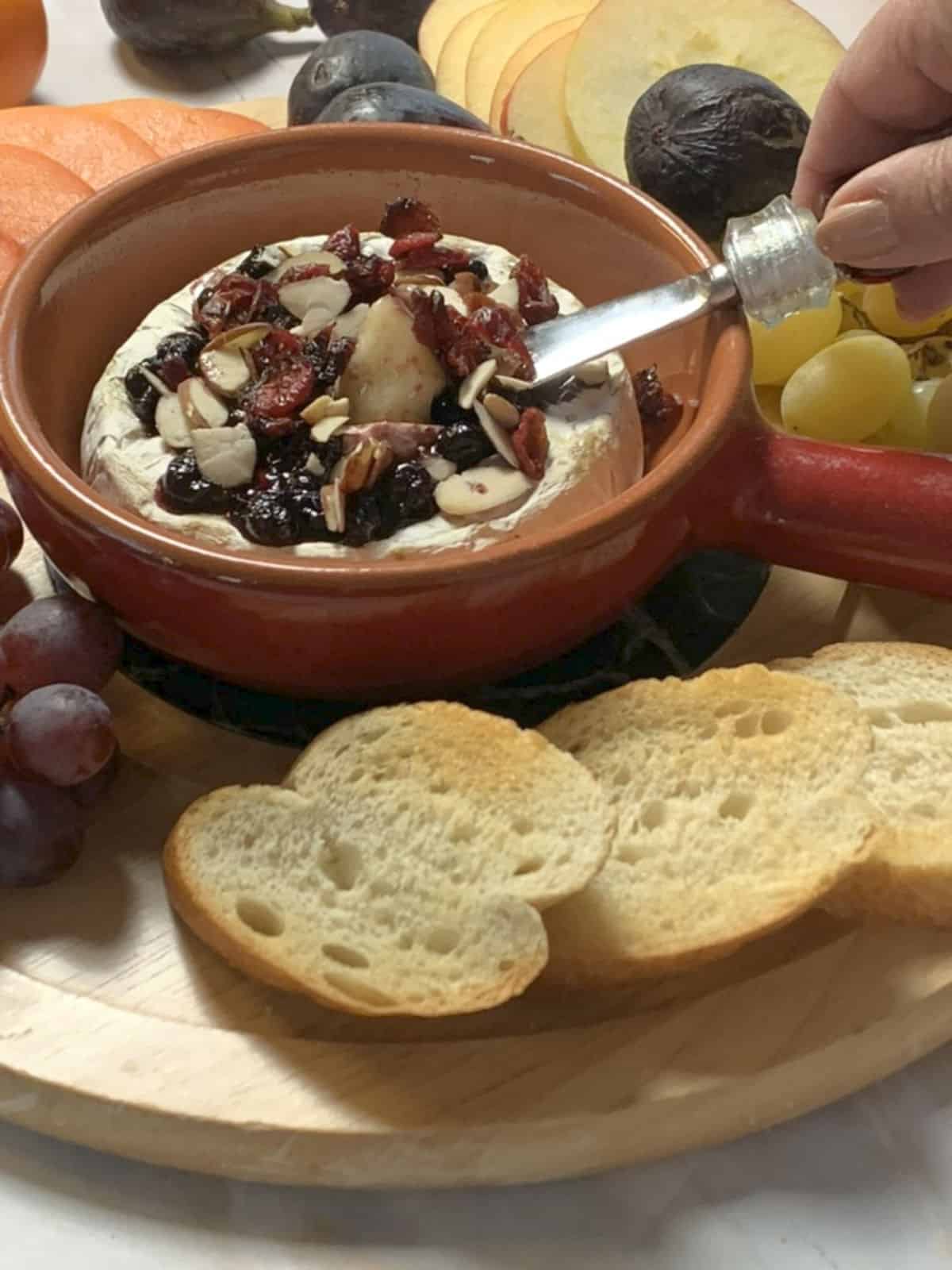 Close-up shot of a small cheese knife scooping baked brie.