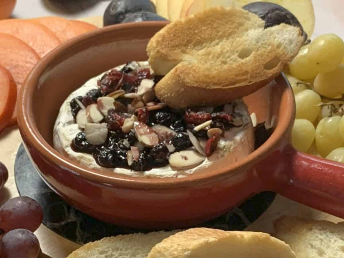 Close-up shot of a baked brie with piece of toasted baguette.
