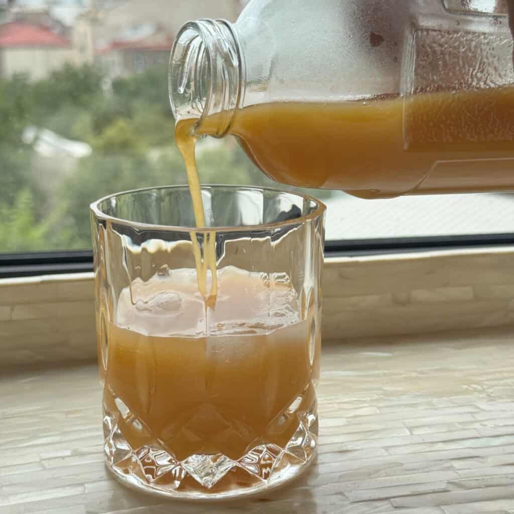 Pouring the apricot nectar juice into a glass.