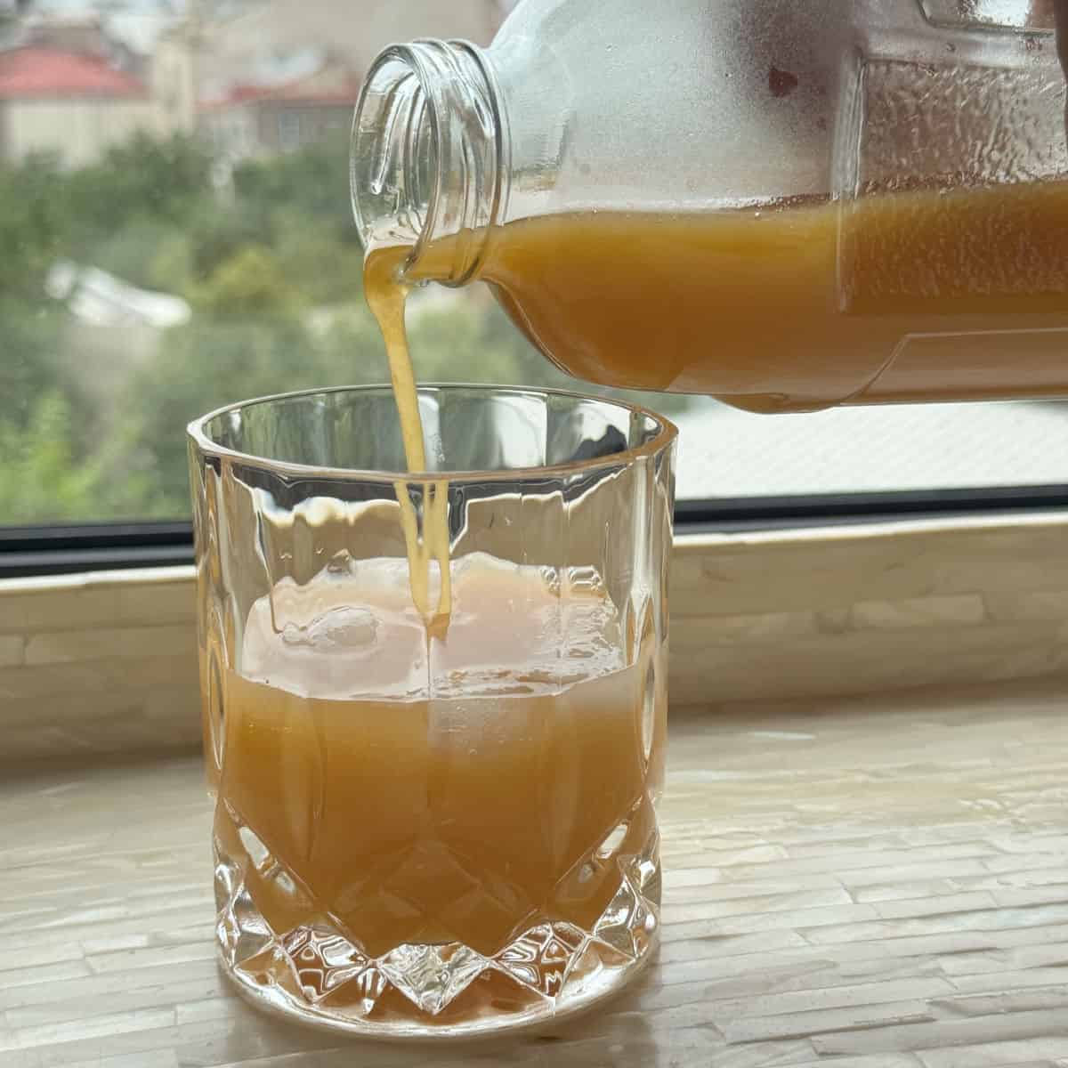 Pouring the apricot nectar juice into a glass.