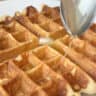 Close-up shot of a kefir waffle with a spoon of dripping honey.