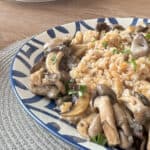 Side view of the farro pilaf with mushroom and plates in the background.