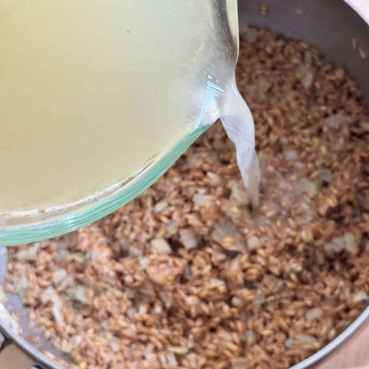 Pouring liquid into the pot with farro.