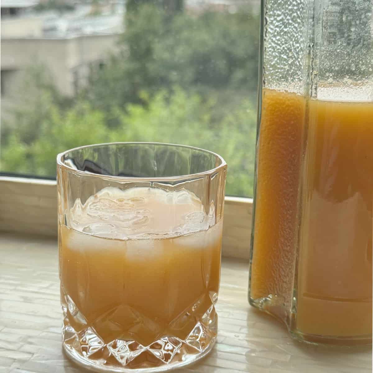 Glass of apricot nectar against the window.